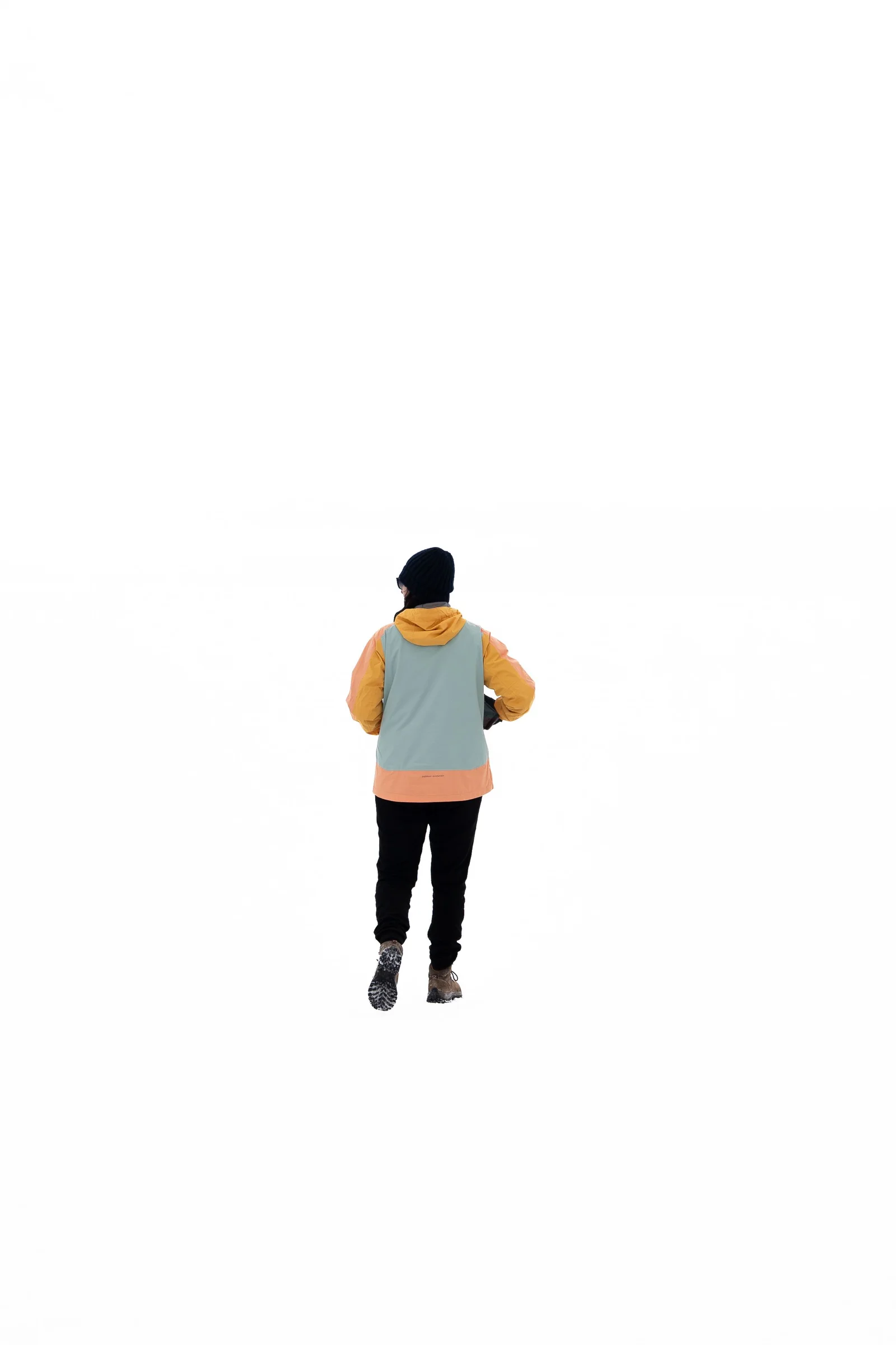 A person in a yellow hood and pale blue vest walks away across the featureless white salt of Salar de Uyuni.